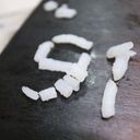 Super close up of grains of cooked white rice resting on a dark wood surface. Together they form the digits nine and one.