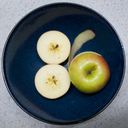 Cut apples in a bowl. Two halves, seeds revealed, form an eight. A strip of peel extending from another apple forms the stroke of a six.