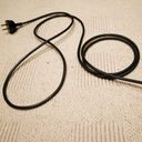 A coiled and looped power cord tracing an eight and a zero on a beige rug.