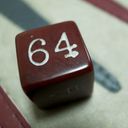 Backgammon die resting on a backgammon board. The top facing value of the die is sixty four.